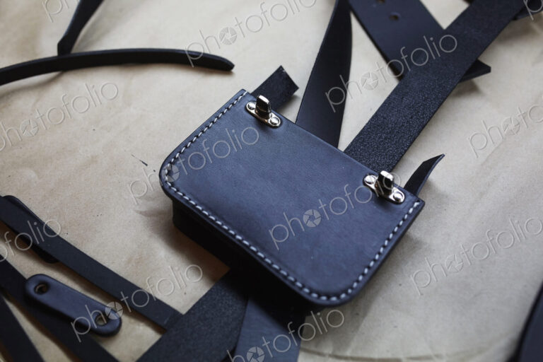 A handmade blue leather bag, strap, component part parts, scissors and hand tools.