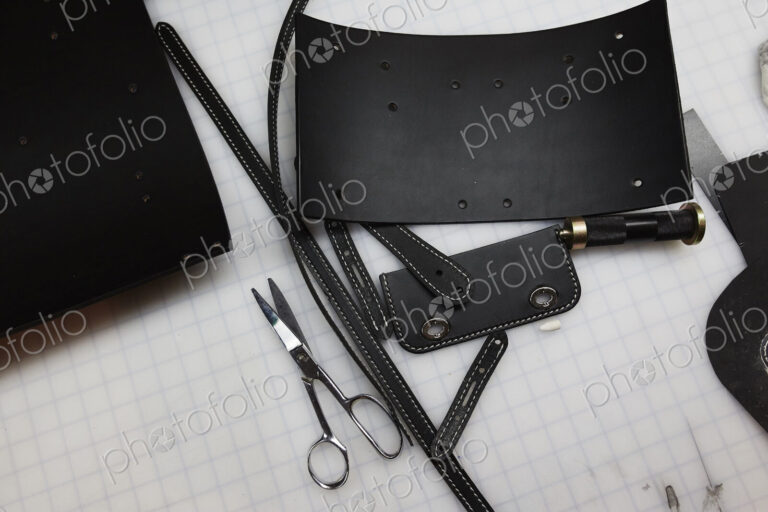 A handmade blue leather bag, strap, component part parts, scissors and hand tools.