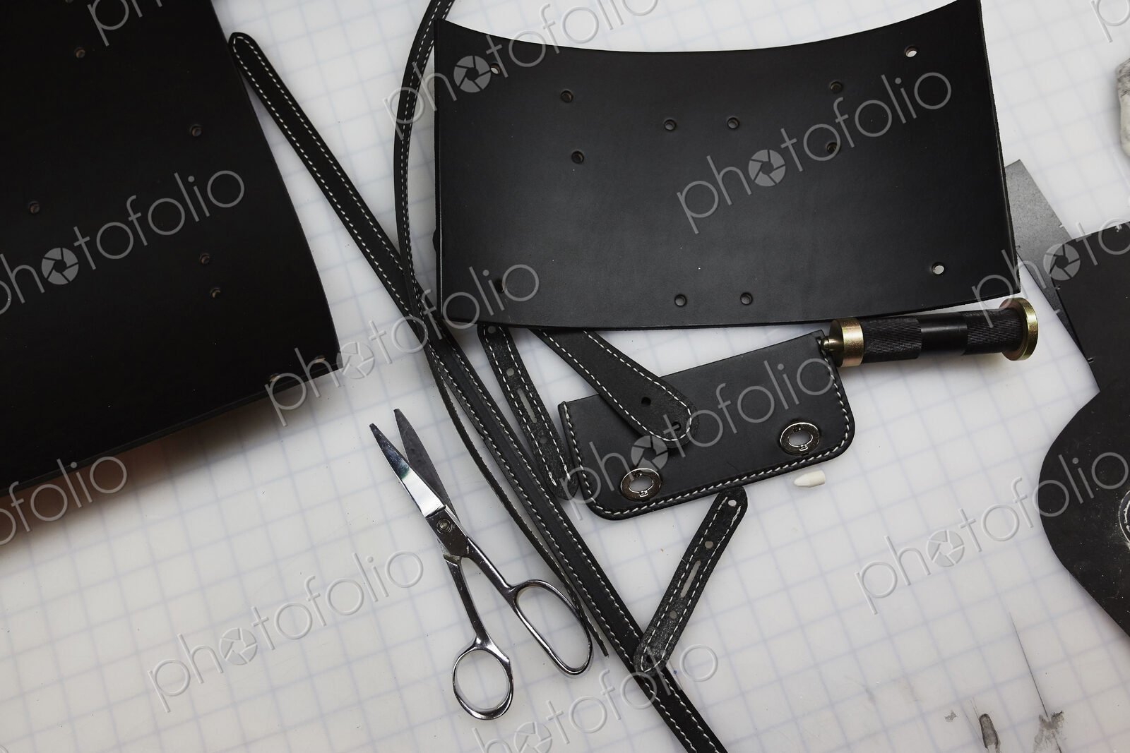 A handmade blue leather bag, strap, component part parts, scissors and hand tools.