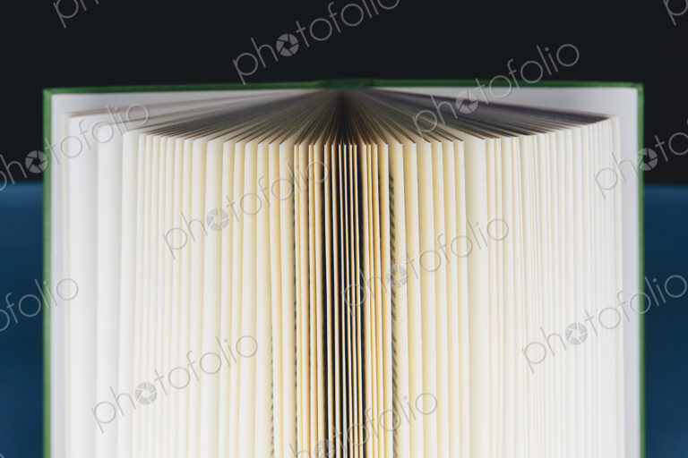 A hard cover printed book, opened and upright. Pages fanned out with graduated…