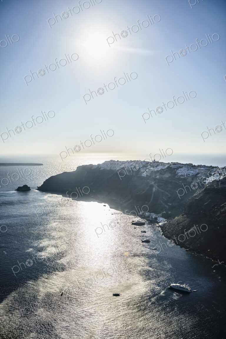 A headland on an island, sun reflecting on water.