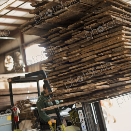 A heap of recycled reclaimed timber planks of wood being moved on a forklift truck.…