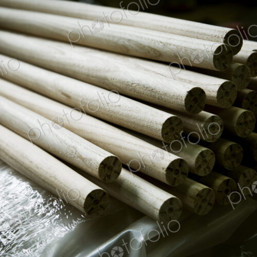 A heap of round smooth wooden poles or components of a wooden chair.