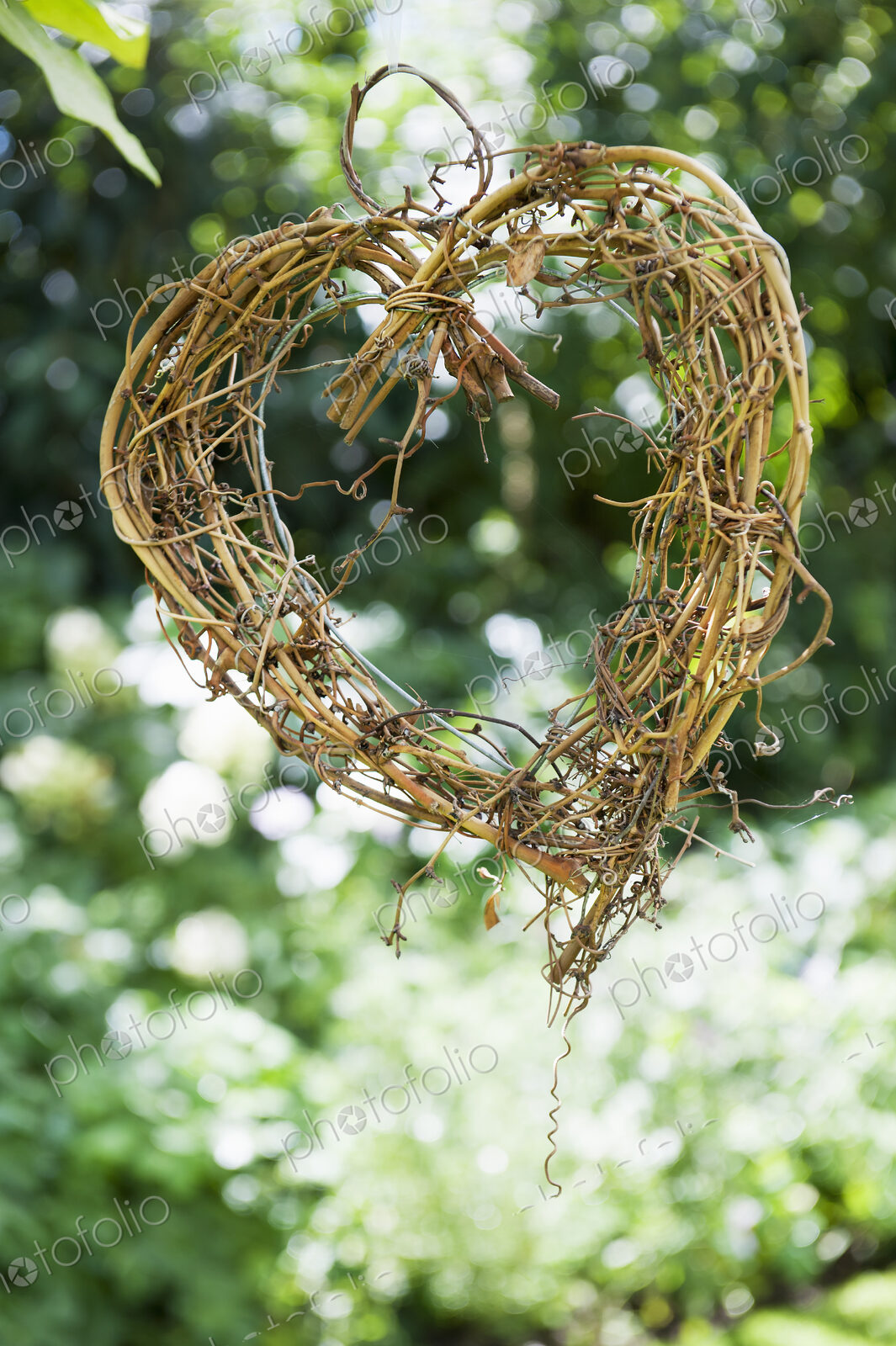 A heart shape made out of woven twigs, hanging from a tree. Simple decorations.