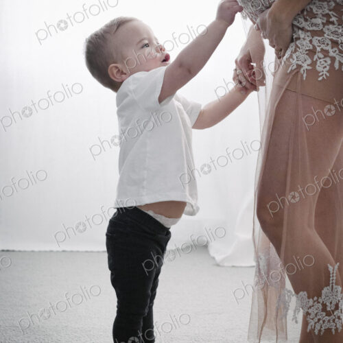 A heavily pregnant woman holding her young son by the hand.