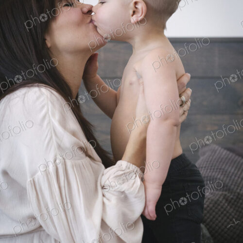 A heavily pregnant woman kissing her young son.