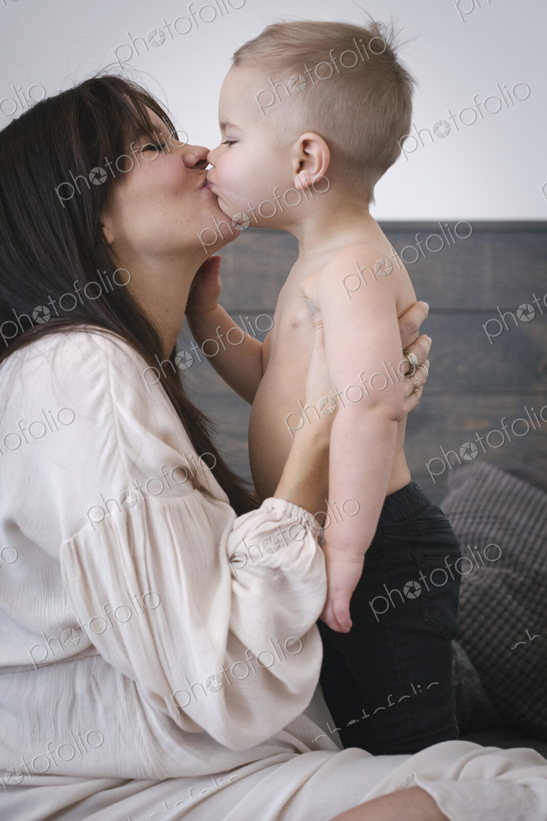 A heavily pregnant woman kissing her young son.