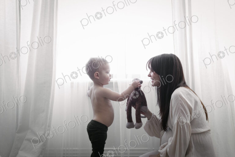 A heavily pregnant woman playing with her young son.