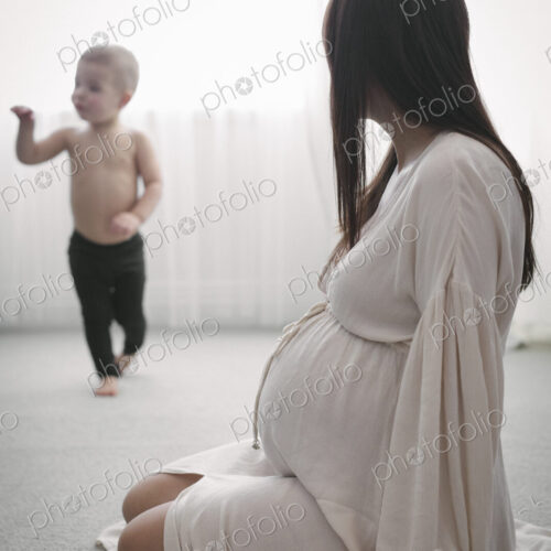 A heavily pregnant woman playing with her young son.
