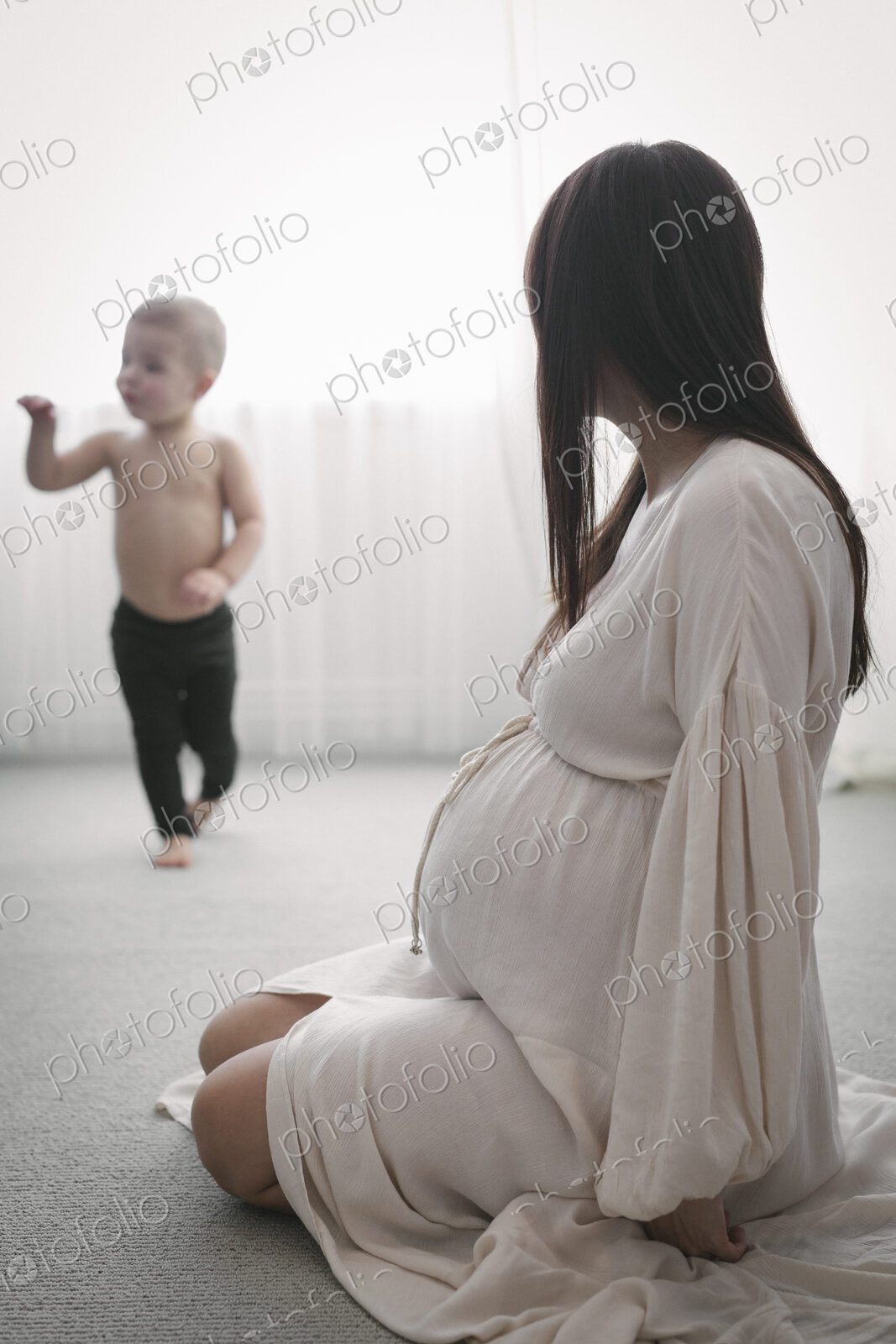 A heavily pregnant woman playing with her young son.