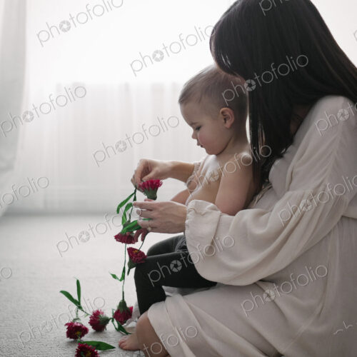 A heavily pregnant woman playing with her young son.