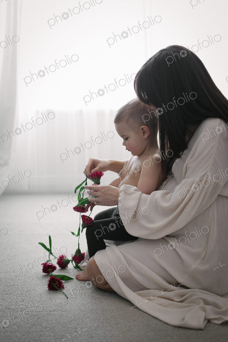 A heavily pregnant woman playing with her young son.