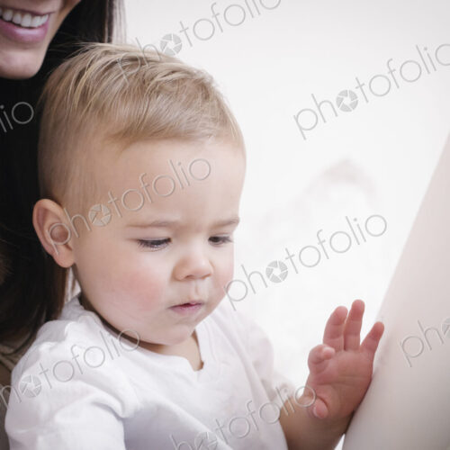 A heavily pregnant woman playing with her young son.