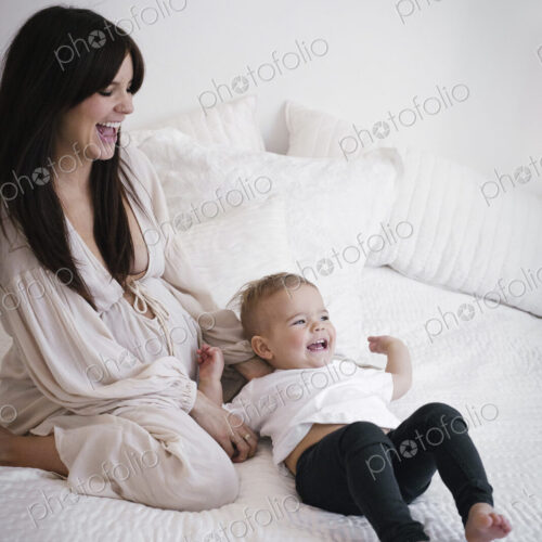 A heavily pregnant woman playing with her young son.