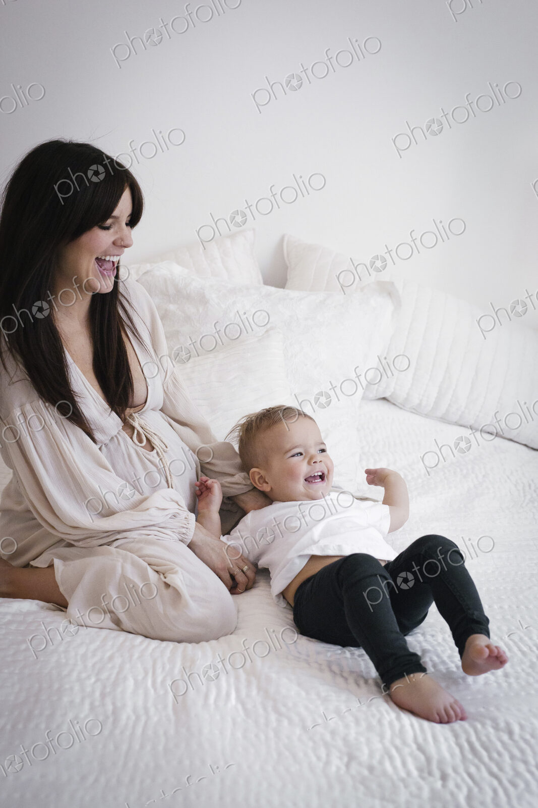 A heavily pregnant woman playing with her young son.