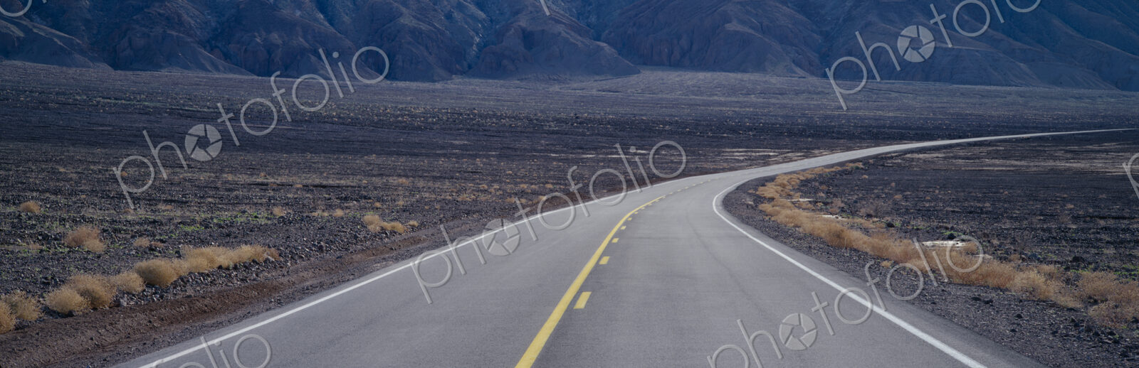 A highway curving through desolate area of Death Valley National Park, California, USA.