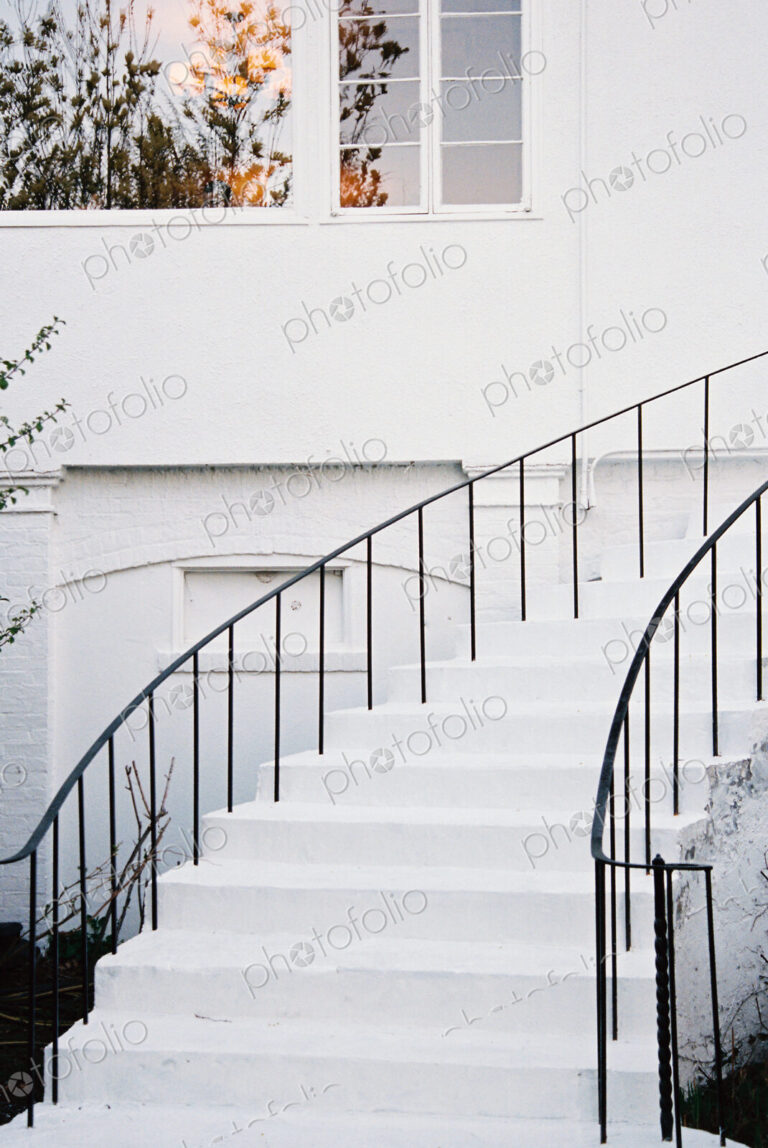 A historic late 18th century house with white walls and a curved exterior staircase