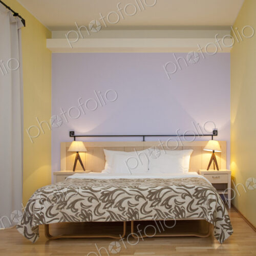 A hotel bedroom, modern furniture and fittings, double bed and bedside lights,…