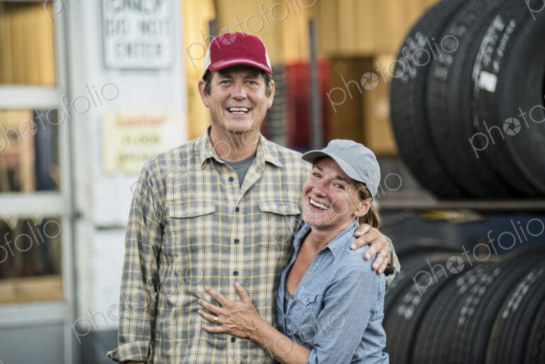 A husband and wife truck driving team near their truck parked in a parking lot at a…