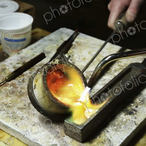A jewellery workshop, molten gold being poured into a small mould. A jewellery workshop, molten gold being poured into a small mould.