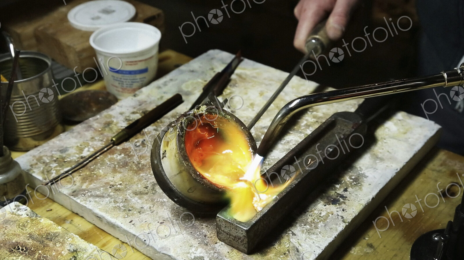 A jewellery workshop, molten gold being poured into a small mould.
