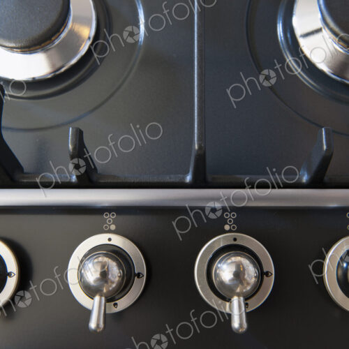 A kitchen stove with gas burners and control knobs.