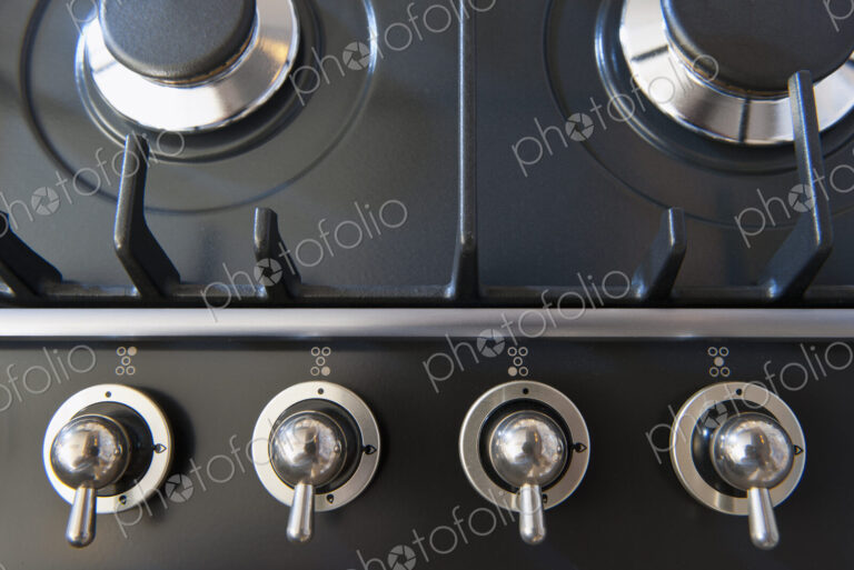 A kitchen stove with gas burners and control knobs.