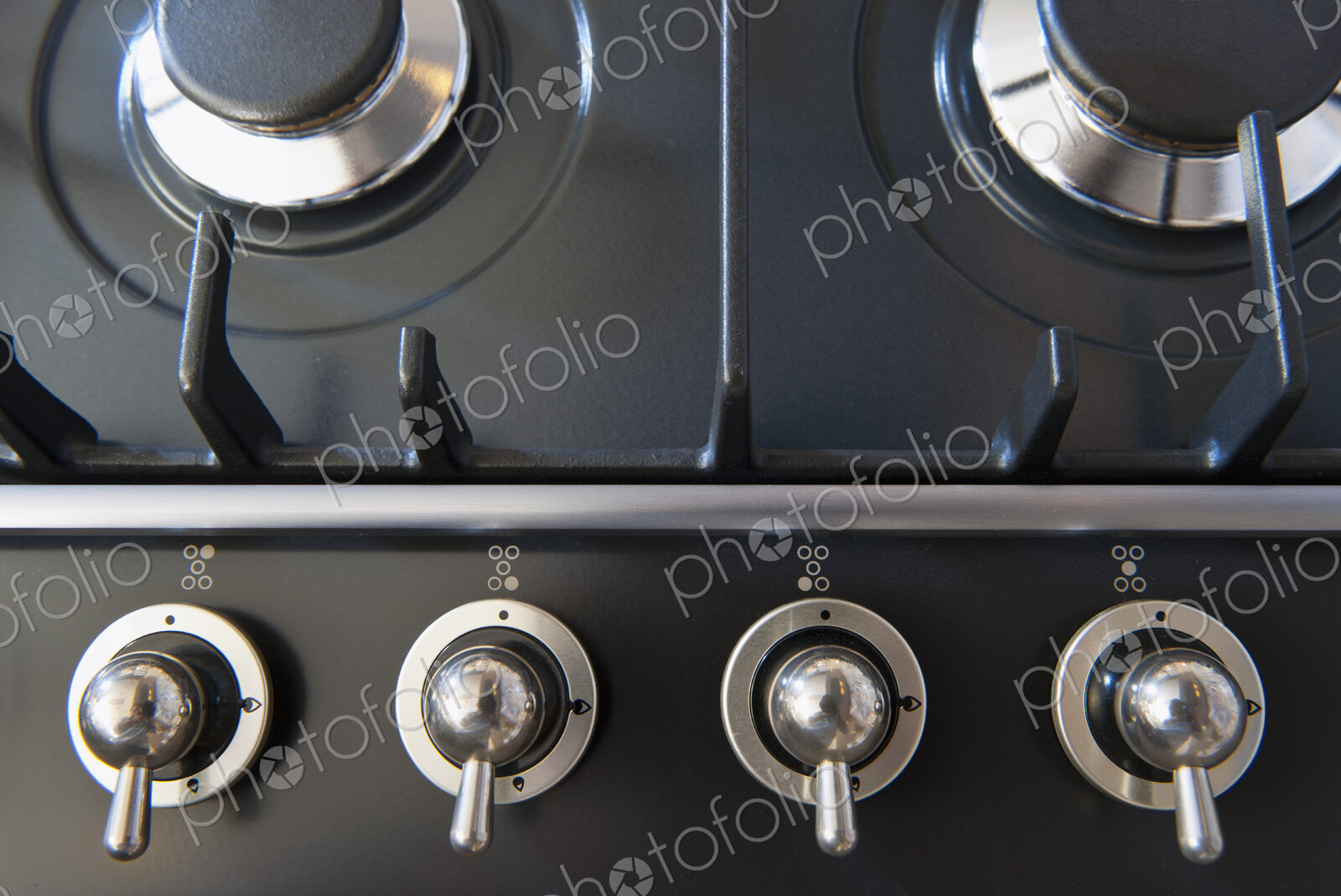 A kitchen stove with gas burners and control knobs.