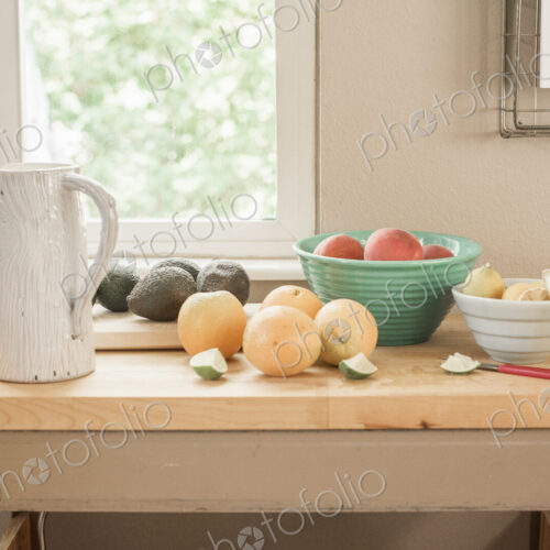 A kitchen table by a window, fresh fruit and avocados in bowls. A kitchen table by a window, fresh fruit and avocados in bowls.