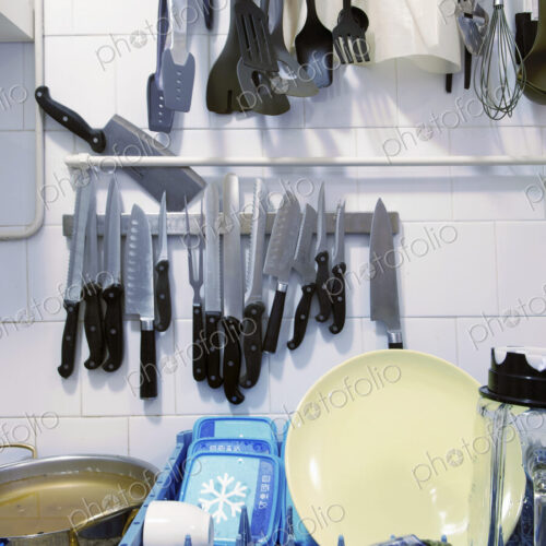 A kitchen with dishes in a rack and hanging storage of knives and kitchen utensils A kitchen with dishes in a rack and hanging storage of knives and kitchen utensils