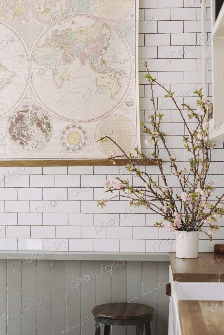 A kitchen worksurface, vase of flowers and a tiled wall.