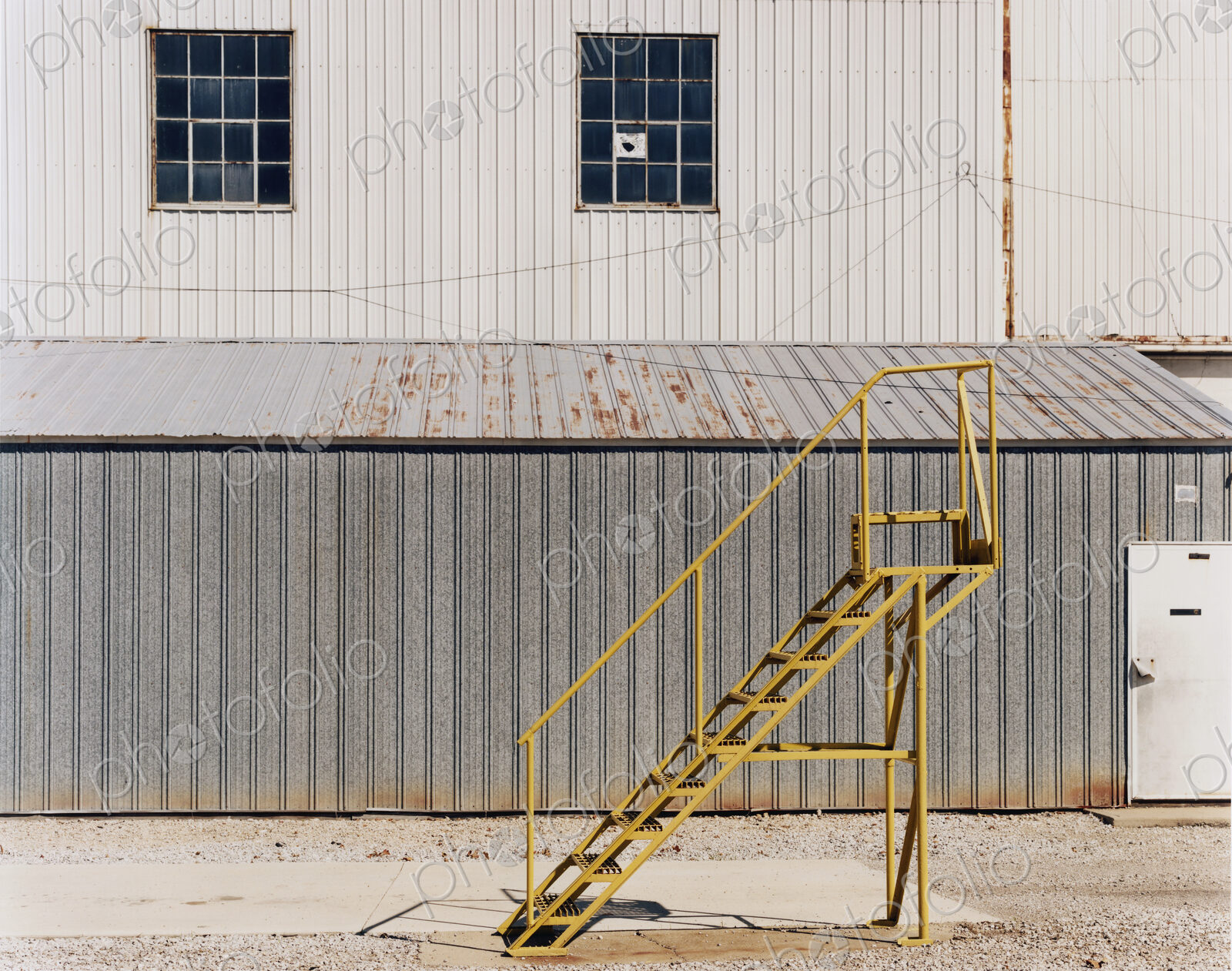 A ladder beside an industrial unit, with corrugated iron walls.