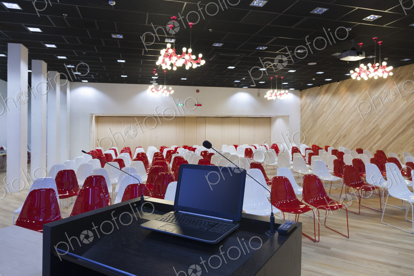 A laptop computer at a podium and rows of chairs in a large room
