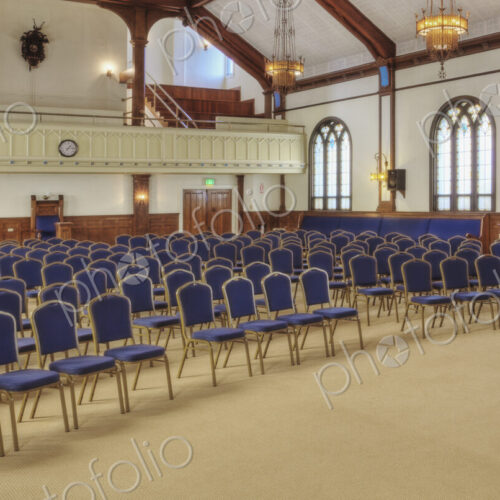 A large auditorium in a historic building, with blue chairs.