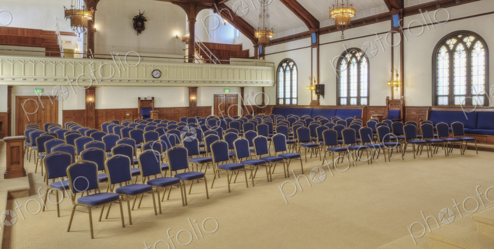 A large auditorium in a historic building, with blue chairs.