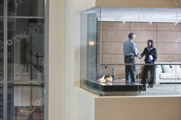 A large building, lobby, view looking into an office with glass walls, two business…