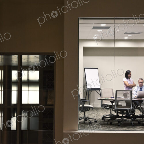 A large building, lobby, view looking into an office with glass walls, two business…