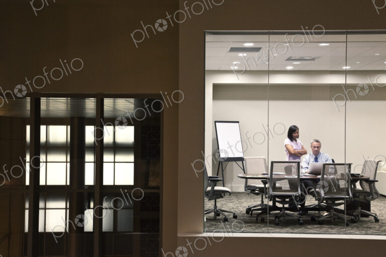 A large building, lobby, view looking into an office with glass walls, two business…