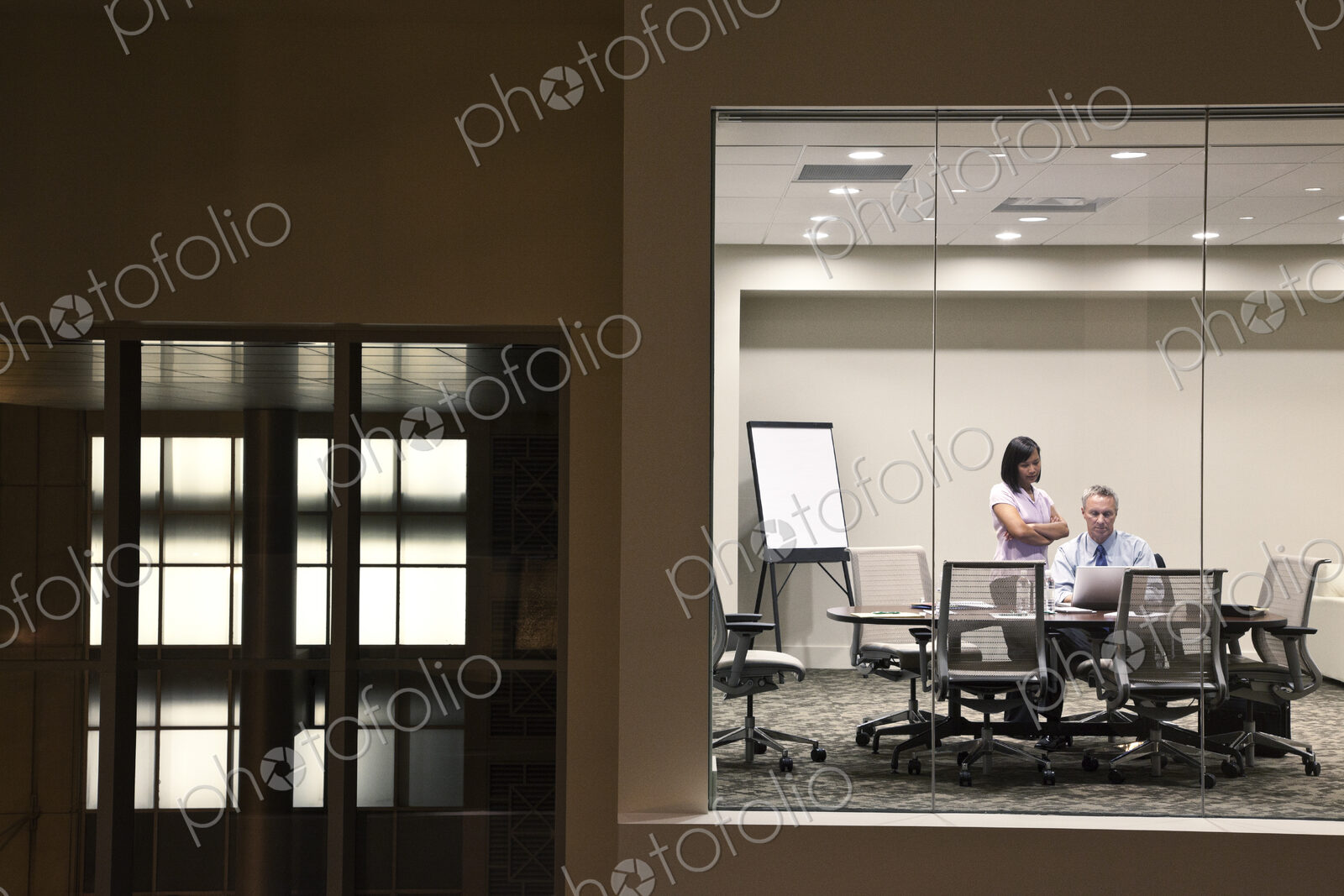 A large building, lobby, view looking into an office with glass walls, two business…