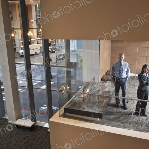 A large building, lobby, view looking into an office with glass walls, two business…