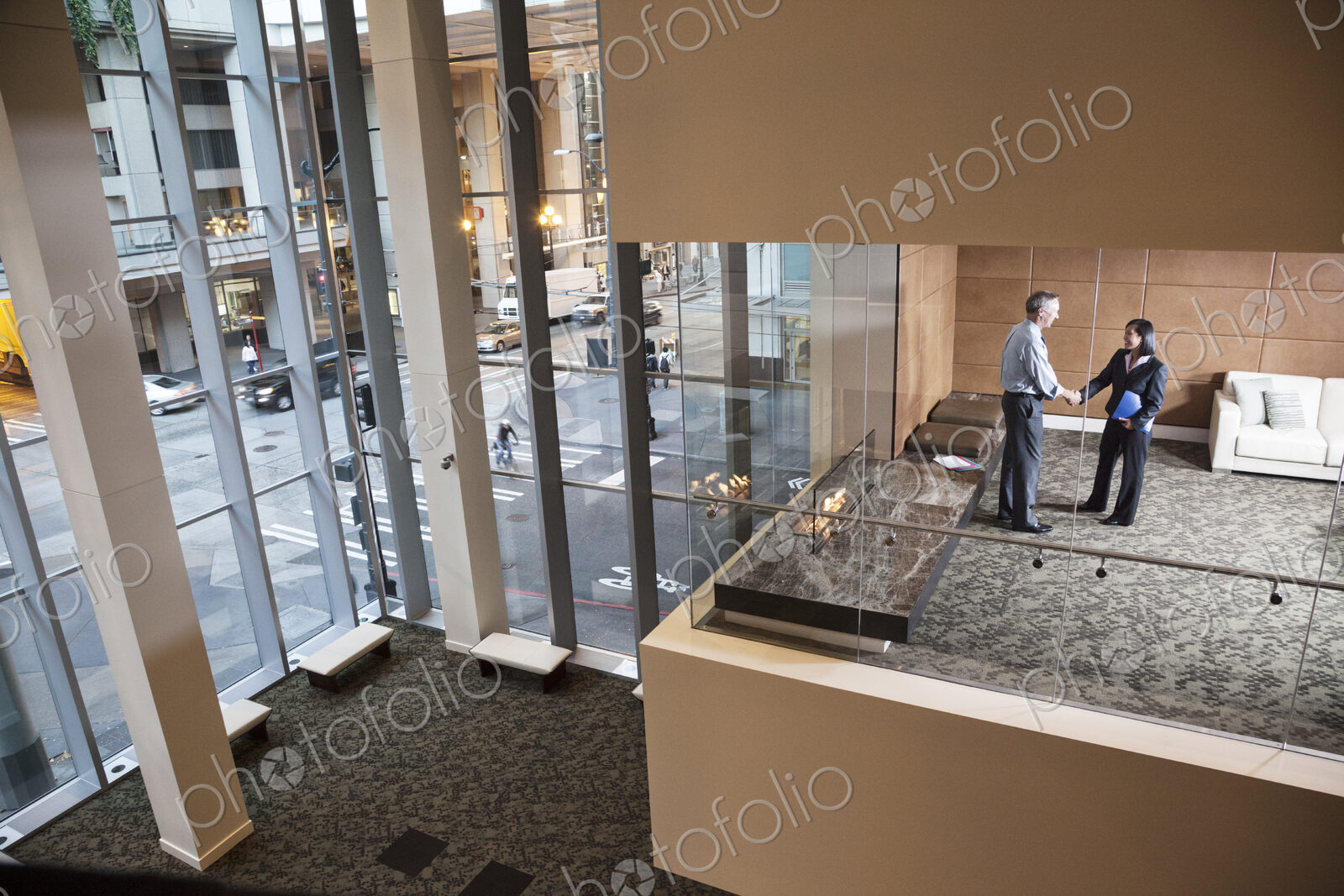 A large building, lobby, view looking into an office with glass walls, two business…