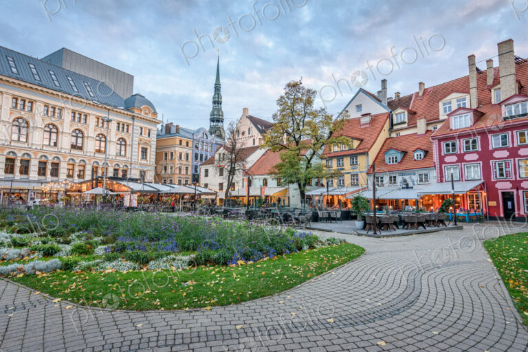 A large cioty square in Riga, historic buildings, cafes and cobbles, with planted…
