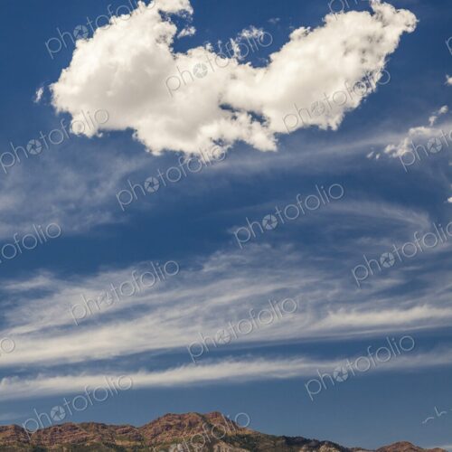 A large cloud drifts over rugged Utah mountains, framed by streaks of high-altitude… A large cloud drifts over rugged Utah mountains, framed by streaks of high-altitude…