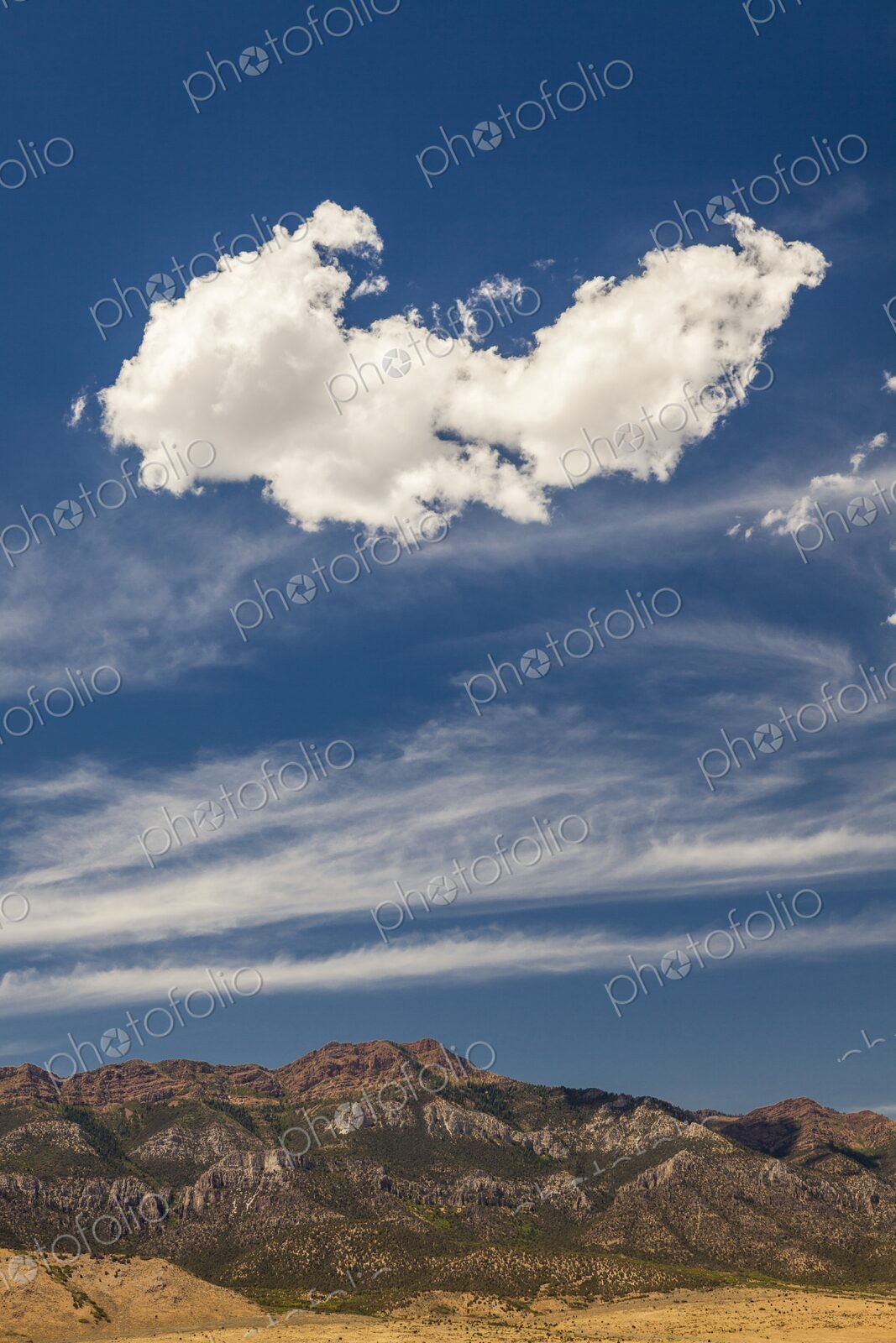 A large cloud drifts over rugged Utah mountains, framed by streaks of high-altitude…