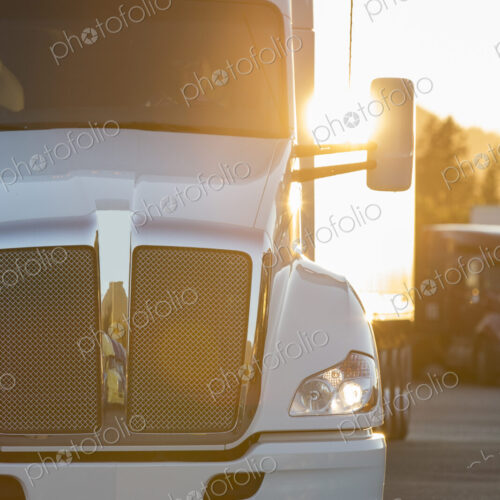 A large commercial truck moving through a truck stop parking lot at sunset. A large commercial truck moving through a truck stop parking lot at sunset.