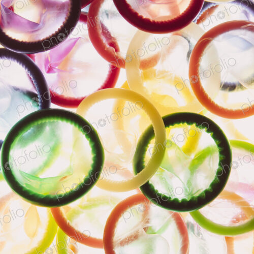 A large group of multi-colored condoms displayed on a white background. Heaped up. A large group of multi-colored condoms displayed on a white background. Heaped up.
