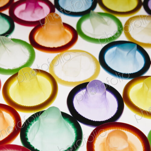 A large group of multi-colored condoms displayed on a white background. Laid out neatly. A large group of multi-colored condoms displayed on a white background. Laid out neatly.