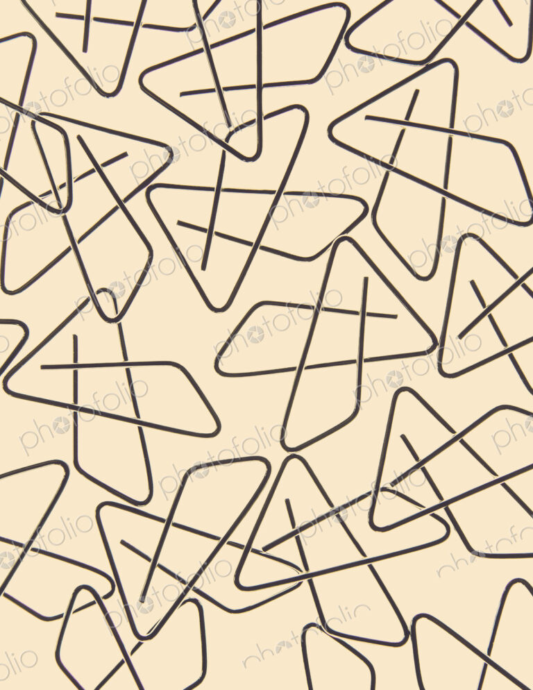 A large group of objects, a type of paperclip, metal bent into a butterfly shape on a…