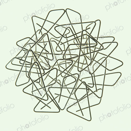A large group of objects, a type of paperclip, metal bent into a butterfly shape on a…