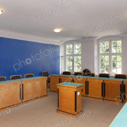 A large meeting room, with desks and chair and central podium, old fashioned decor,…